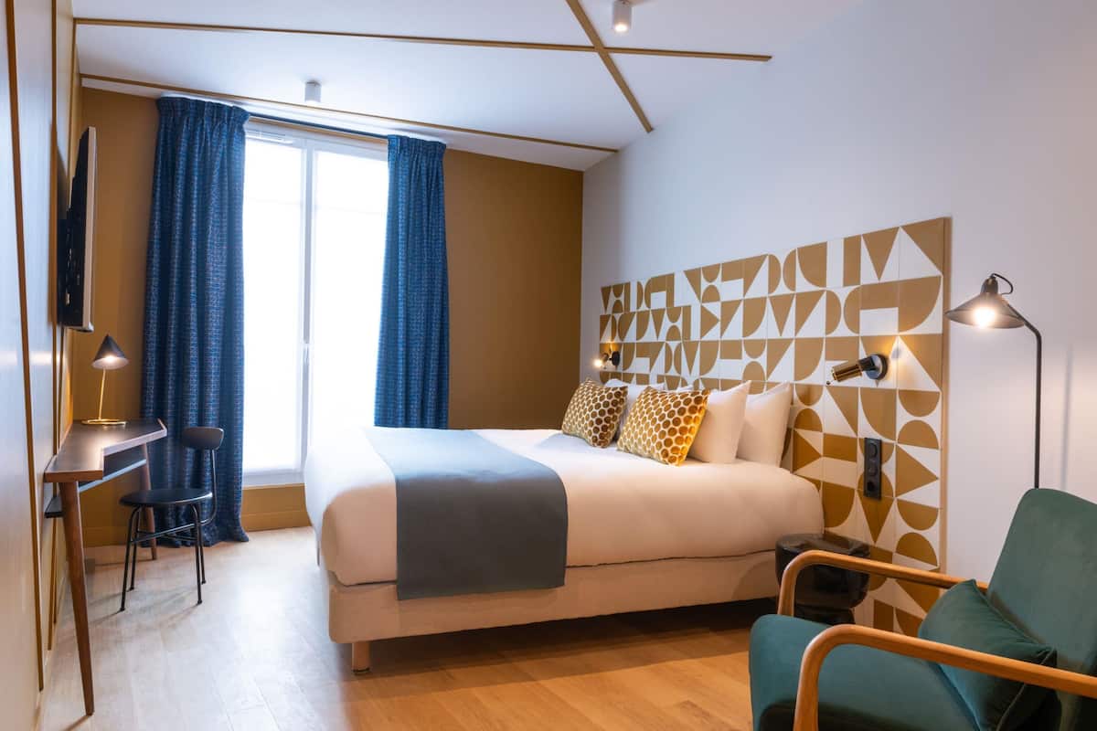 Ein modernes Hotelzimmer mit einem großen Bett, einem Schreibtisch und einem Stuhl.