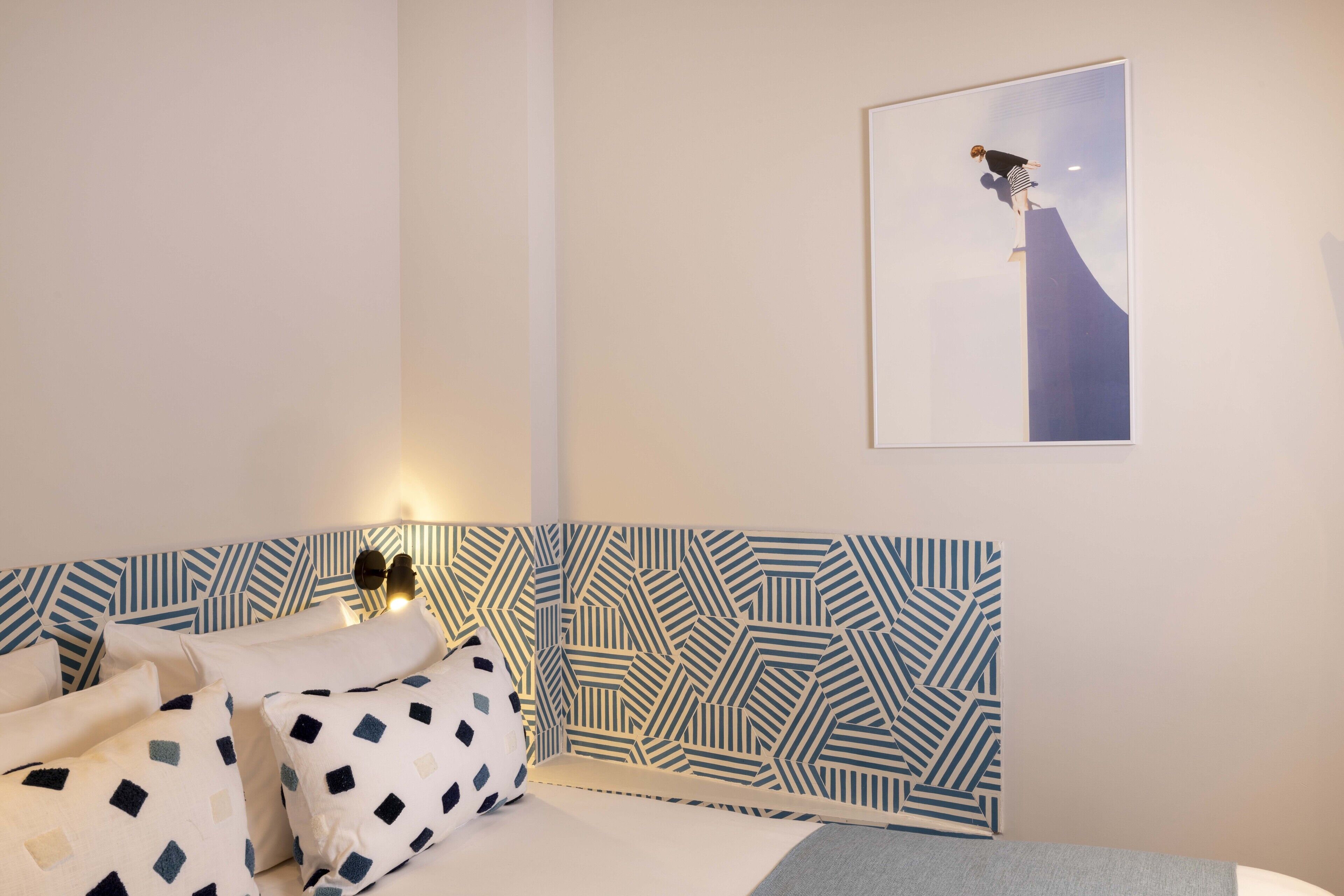Un dormitorio con cabecera estampada, una cama con almohadas y un cuadro en la pared.