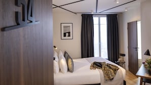 Een moderne hotelkamer met een groot bed, een bureau en een raam met gordijnen.