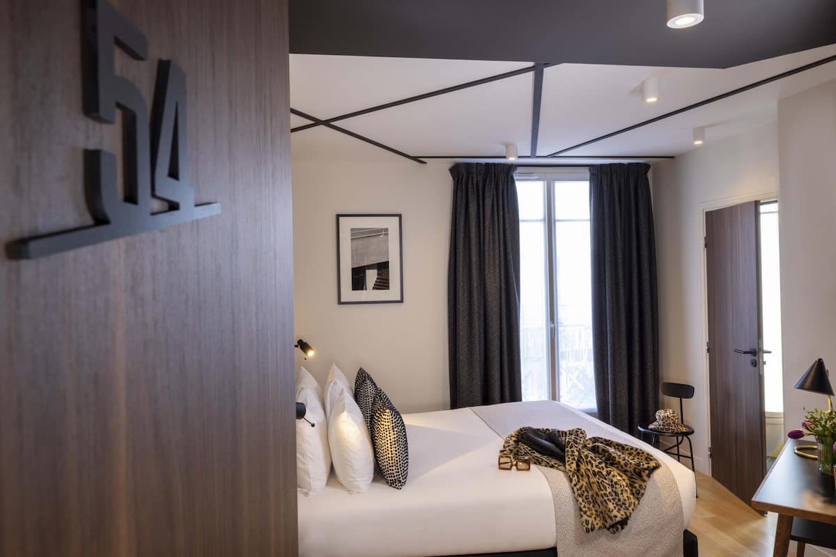 Ein modernes Hotelzimmer mit einem großen Bett, einem Schreibtisch und einem Fenster mit Vorhängen.