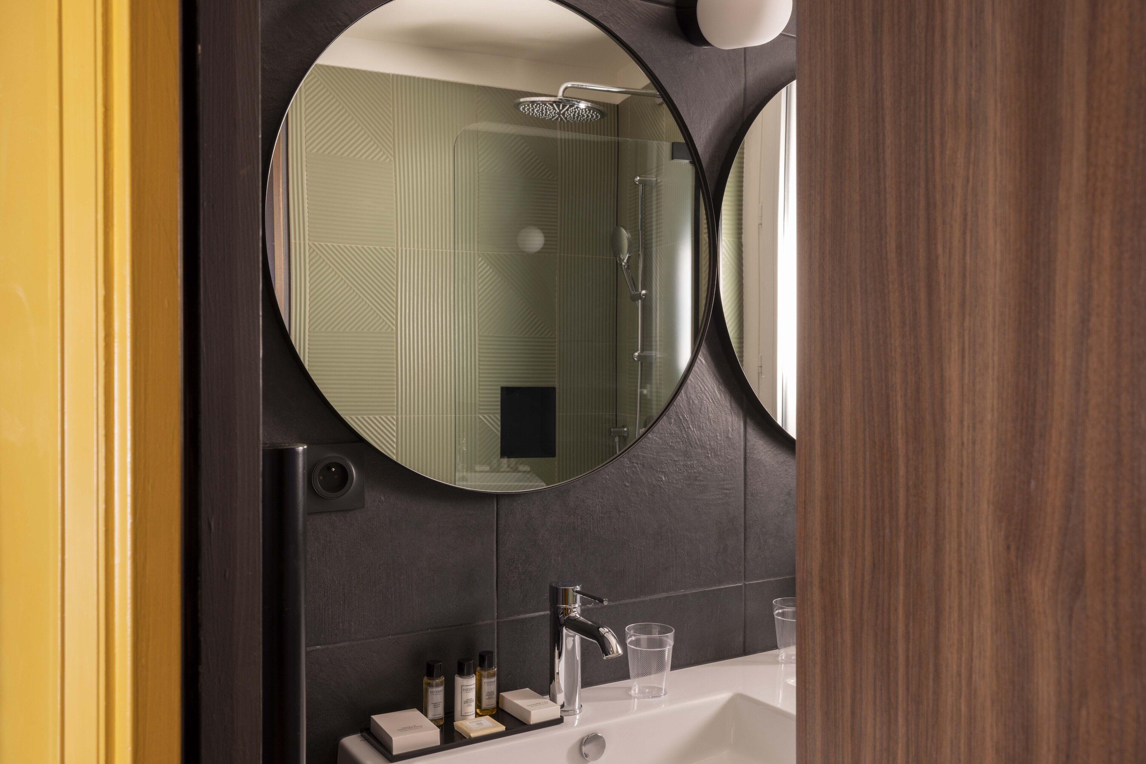 Un baño con un espejo grande, un lavabo y una ducha.