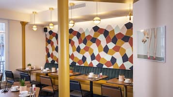 Un comedor moderno con paredes de diseño geométrico, varias mesas y sillas.