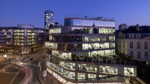 Een meerhoog gebouw met grote glasramen, een gebogen gevel en een terras op het dak.