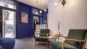 Een modern interieur met een receptiebalie, groene bekleden stoelen en een visgraatvloer.