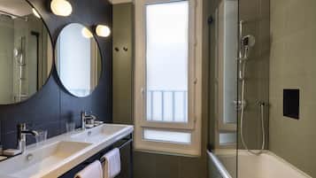 Un baño moderno con dos lavamanos, un espejo grande, ducha envuelta en vidrio y vistas a través de una ventana.