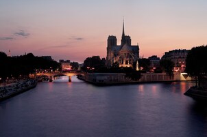 A river with a bridge and a large cathedral in the background.