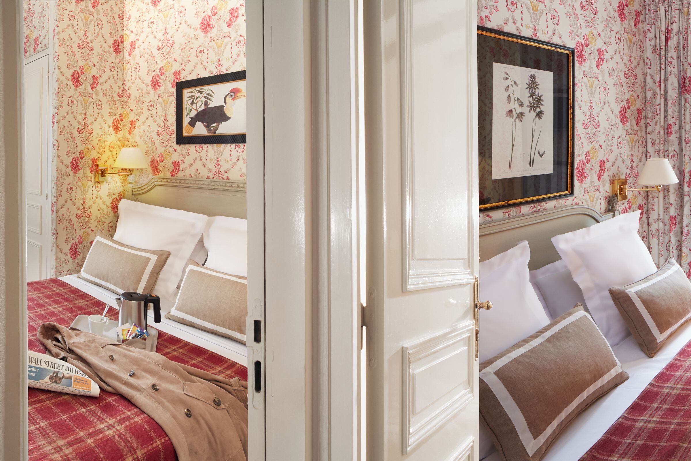 A hotel room with a bed, a framed picture, a lamp, and a tray with a newspaper.