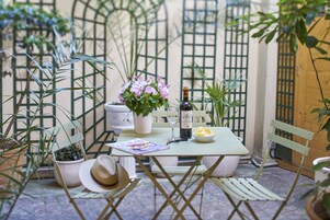 A table set with a bottle, glasses, a bowl of chips, and a magazine.