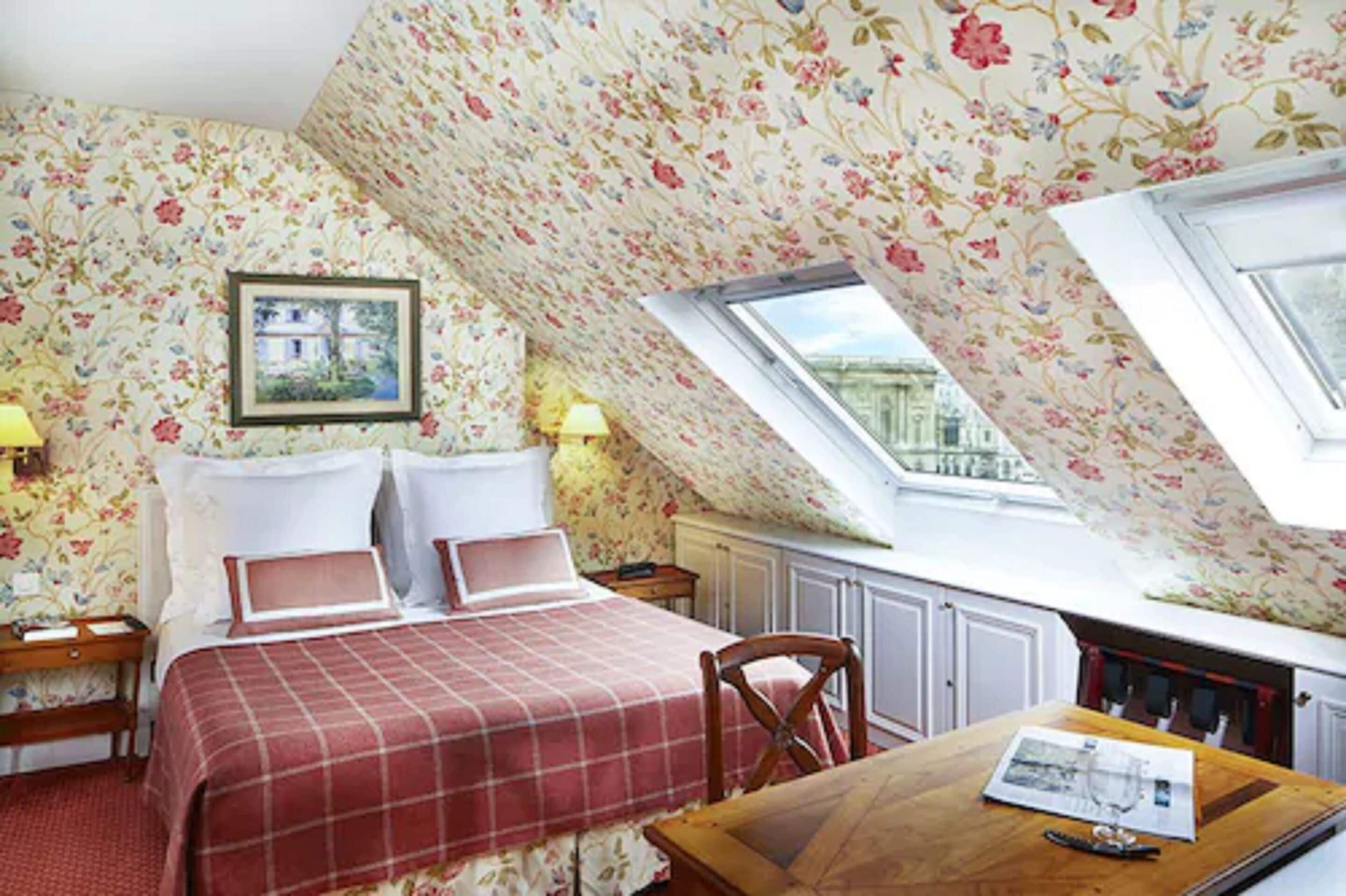 A bedroom with a bed, a desk, and a window.