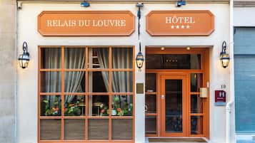 Experience the charm of RELAIS DU LOUVRE HOTEL, where elegant windows and a beautiful floral arrangement greet you at the entrance.