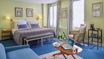 A hotel room with a bed, a desk with a laptop, a chair, and a blue sofa.
