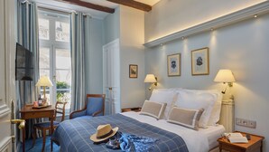 A hotel room with a bed, two bedside tables, a desk, a chair, and a window with curtains. - Relais Du Louvre (Paris)