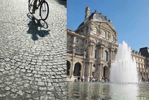 A cobblestone street with a bicycle and a historic building with a fountain.