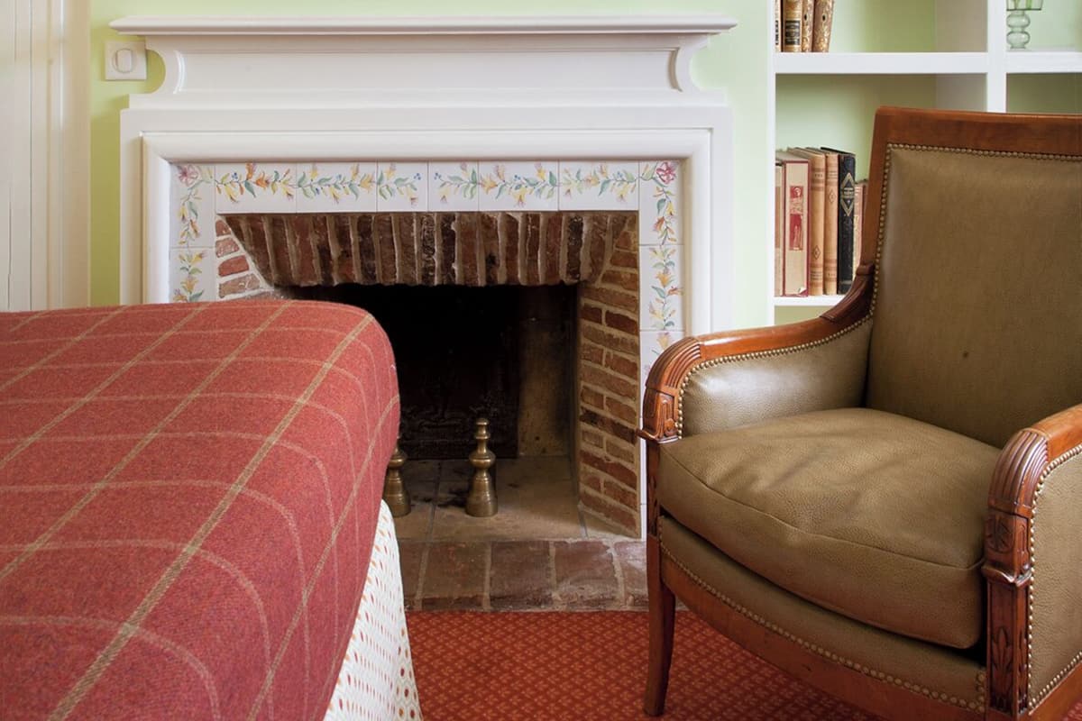 A room with a fireplace, a bookshelf, a mirror, and a chair.