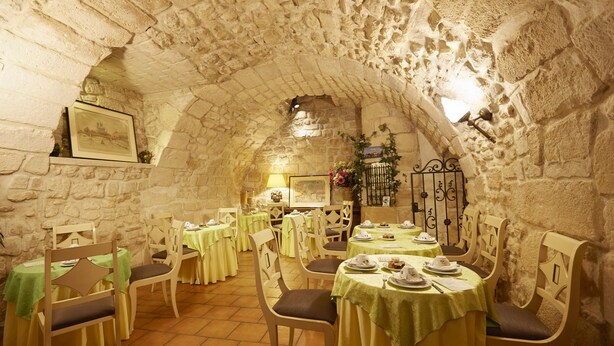 A restaurant with stone walls, round tables, and chairs. - Hotel Beaubourg (Paris)