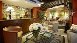 A hotel lobby with a reception desk, seating area, and a large potted plant. - Hotel Beaubourg (Paris)