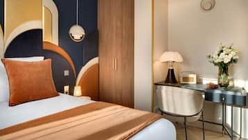 Une chambre d’hôtel avec un lit, un bureau, une chaise, une lampe et un vase avec des fleurs.