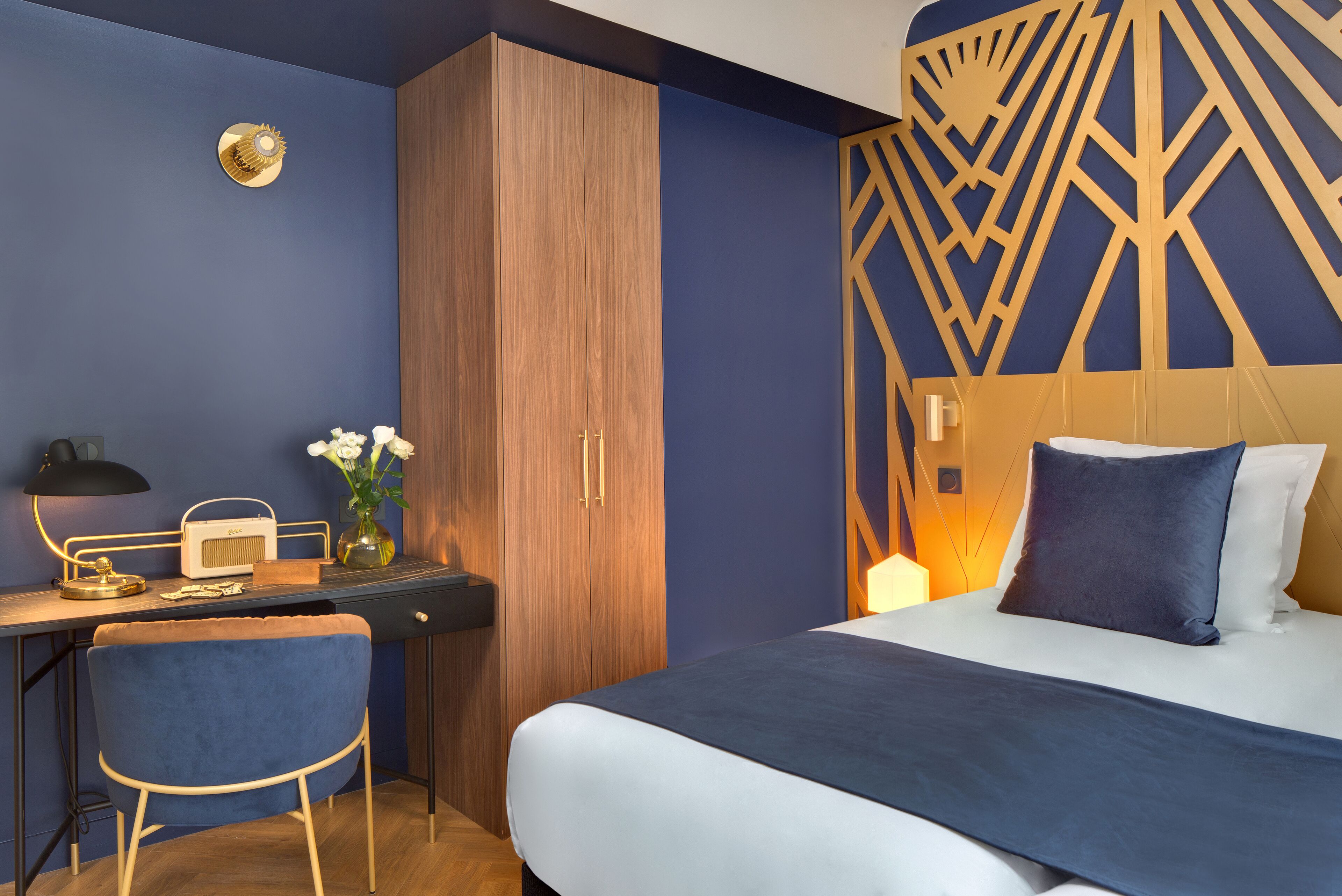 A bedroom with a bed, a desk with a chair, and a wardrobe.