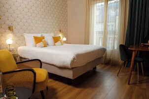 Una camera d'albergo ordinata con un letto grande, due lampade sui comodini, un tavolo da pranzo e sedie.