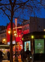 A city street at dusk with illuminated buildings and a bus.