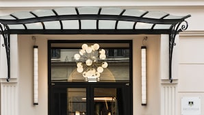 L'ingresso di un edificio con una porta in vetro, un cartello con la scritta 'ARTEMISIA' e un lampadario decorativo sopra la porta.