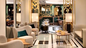 Una moderna hall d'albergo con una zona salotto centrale, un bar e un'area ristorazione.
