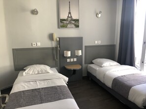 A hotel room with two beds, a small table, a wall-mounted phone, and a picture of the Eiffel Tower. - Hotel Clauzel (Paris)