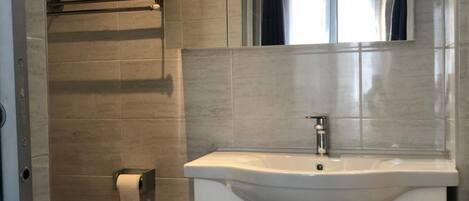 A bathroom with a toilet, a sink with a mirror above it, and a shower area.