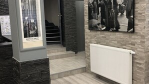 Zona de recepción con pared de piedra, un cartel de un paisaje urbano y un cartel de escena histórica.