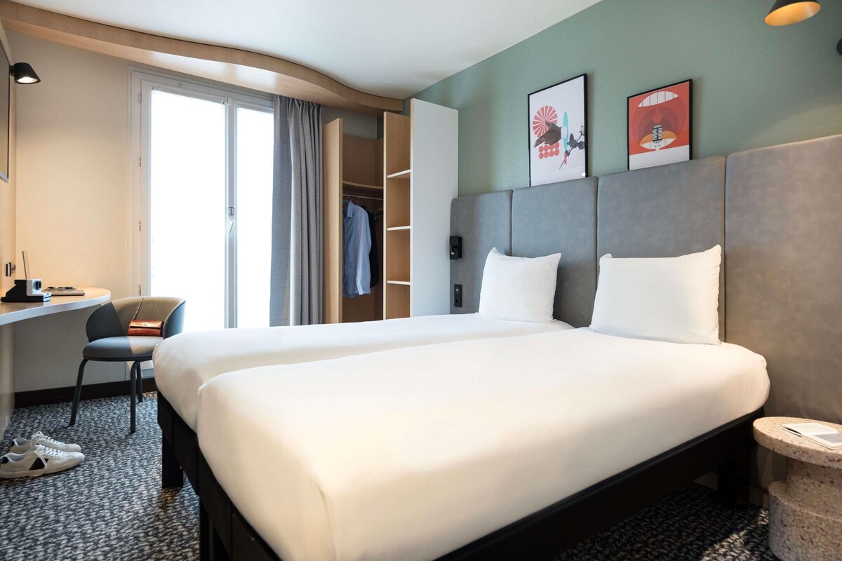 Une chambre d’hôtel avec un grand lit, un bureau, une chaise, une armoire et une petite table ronde.