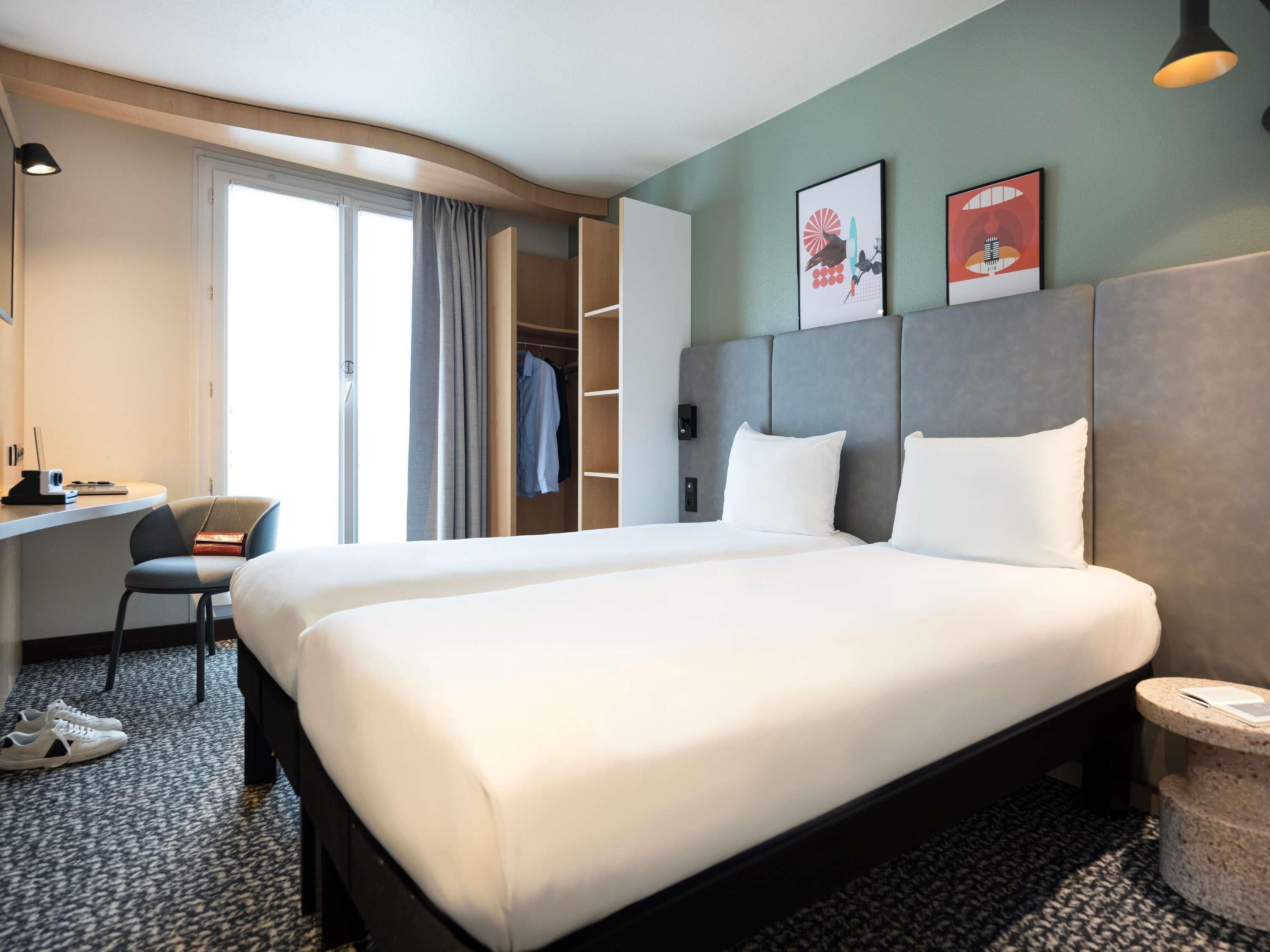 Une chambre d’hôtel avec un grand lit, un bureau, une chaise, une armoire et une petite table ronde.