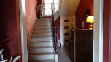 A staircase leading to a landing with a fire extinguisher and a vase of flowers.