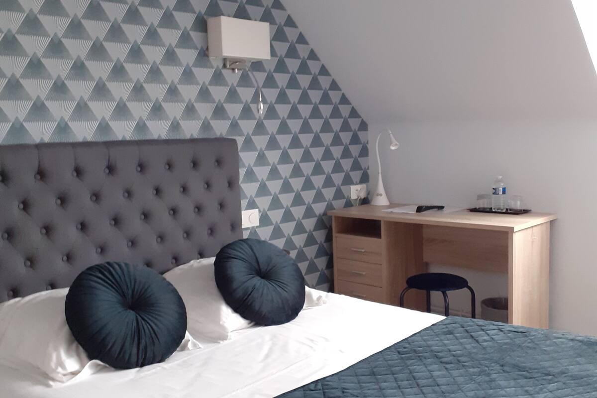 Een slaapkamer met een bed, een bureau en een stoel.