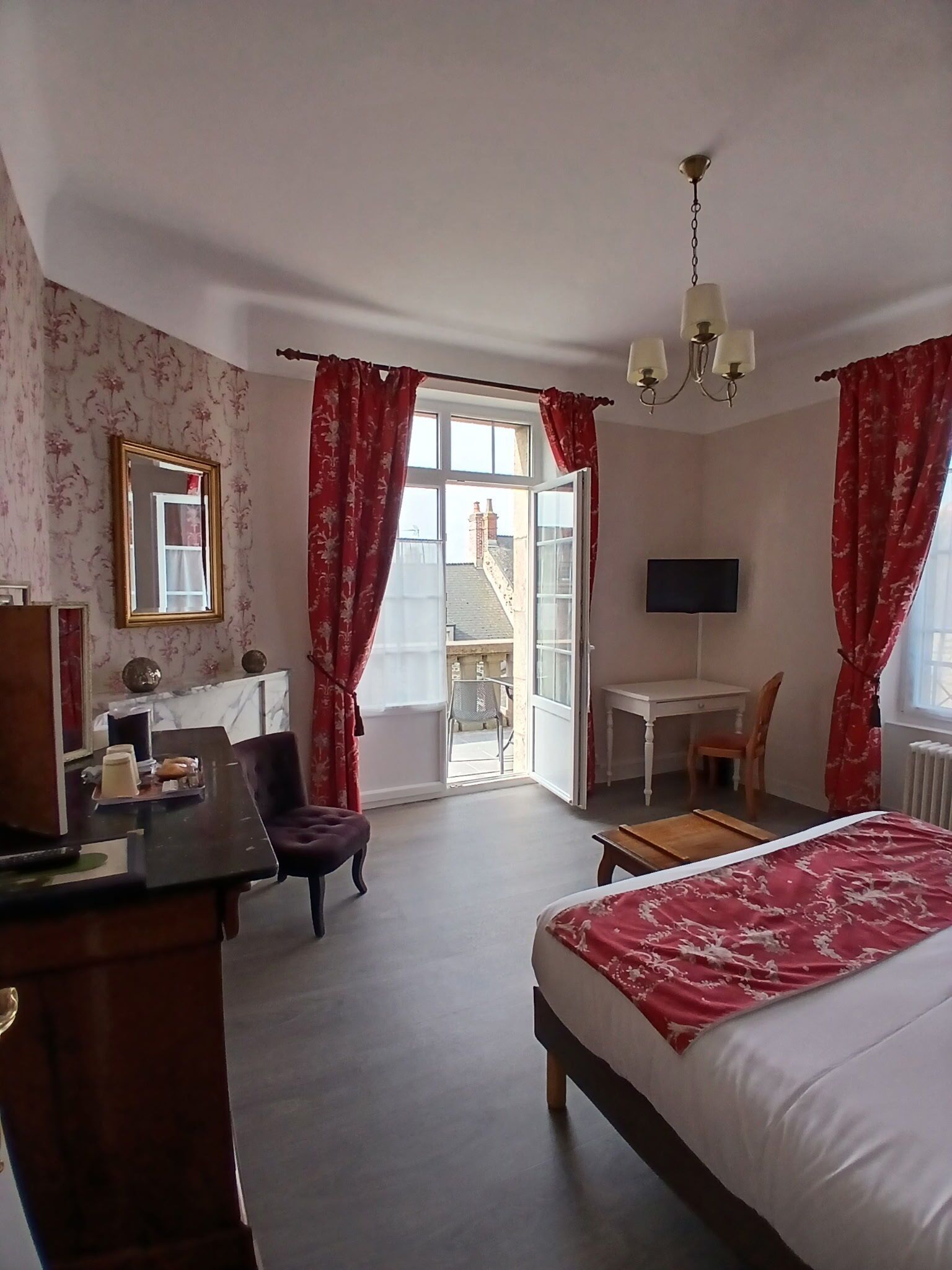 Une chambre d’hôtel avec un lit, un bureau, une chaise et une vue sur l’extérieur.
