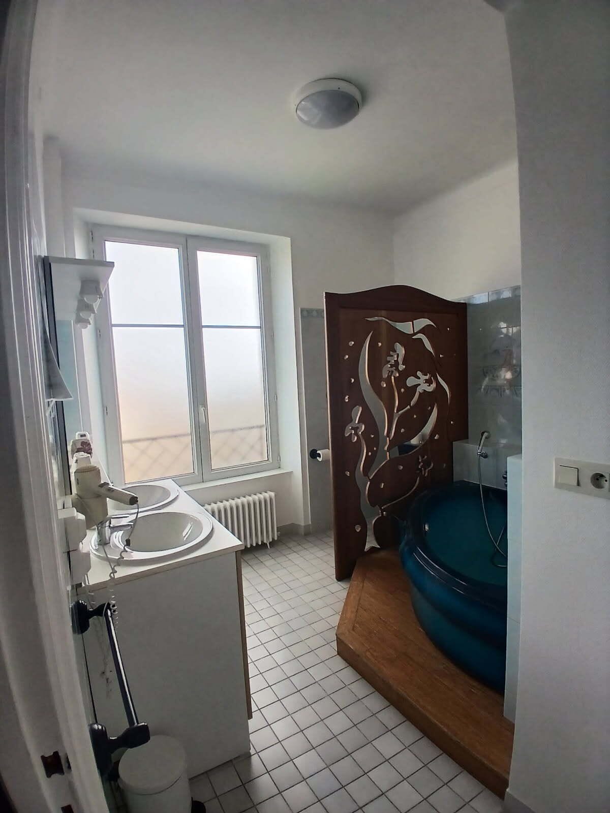 Ein Badezimmer mit einem weißen Waschbecken, einer Toilette, einer Dusche und einem großen Fenster.