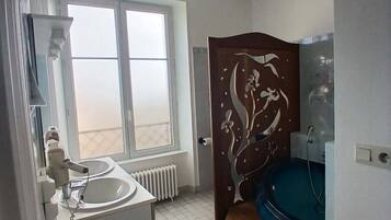 Ein Badezimmer mit einem weißen Waschbecken, einer Toilette, einer Dusche und einem großen Fenster.