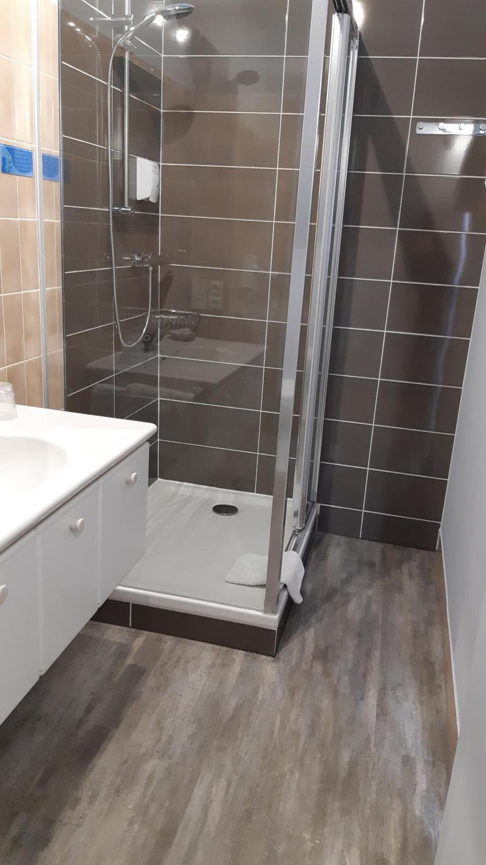 A modern bathroom with a glass-enclosed shower, a white sink, and a wooden floor.