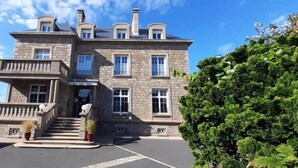 A large stone building with a grand entrance, multiple windows, and a well-maintained lawn.