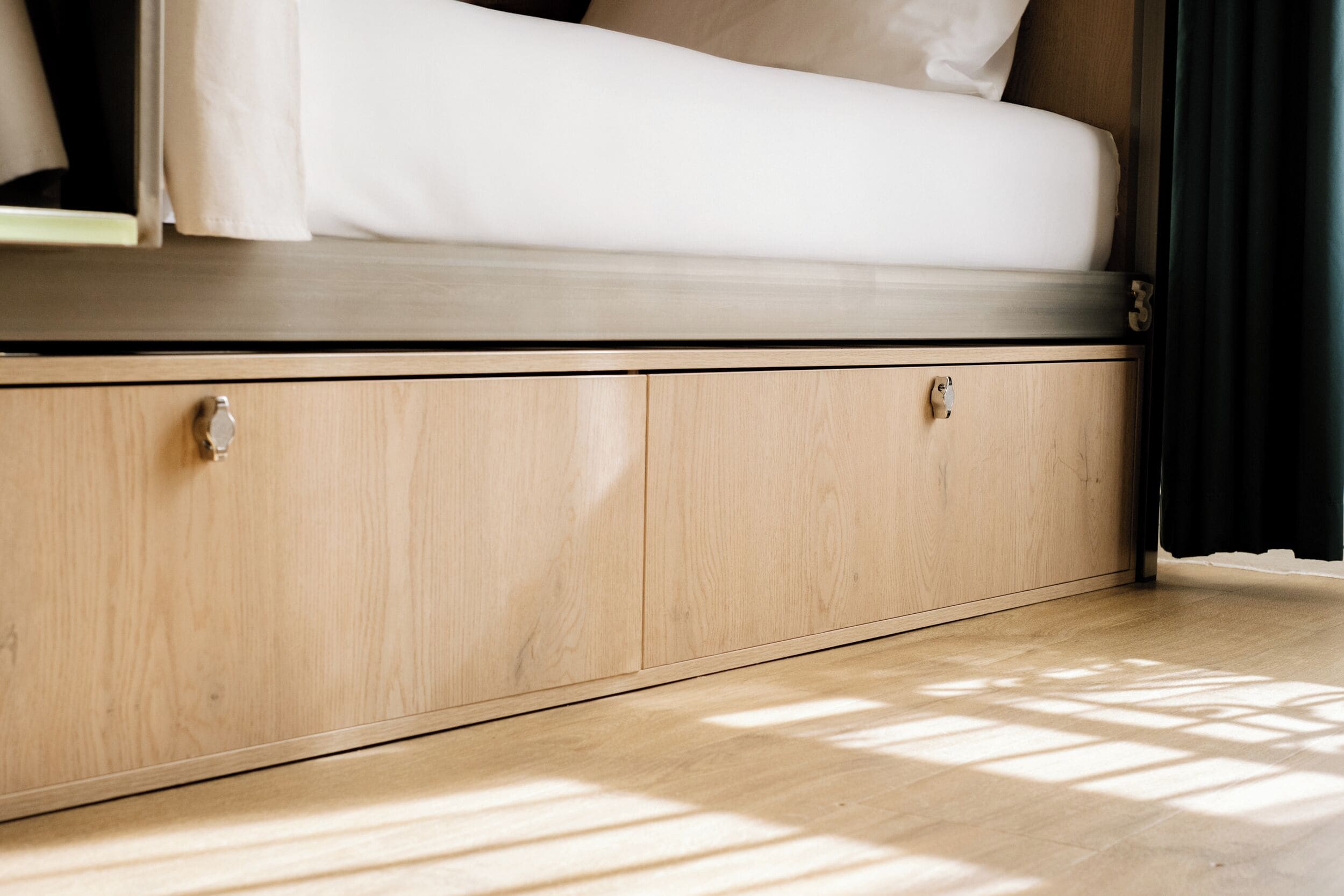 Ein Bett mit Holz-Kopfteil und einem Unterschrank mit Griff.
