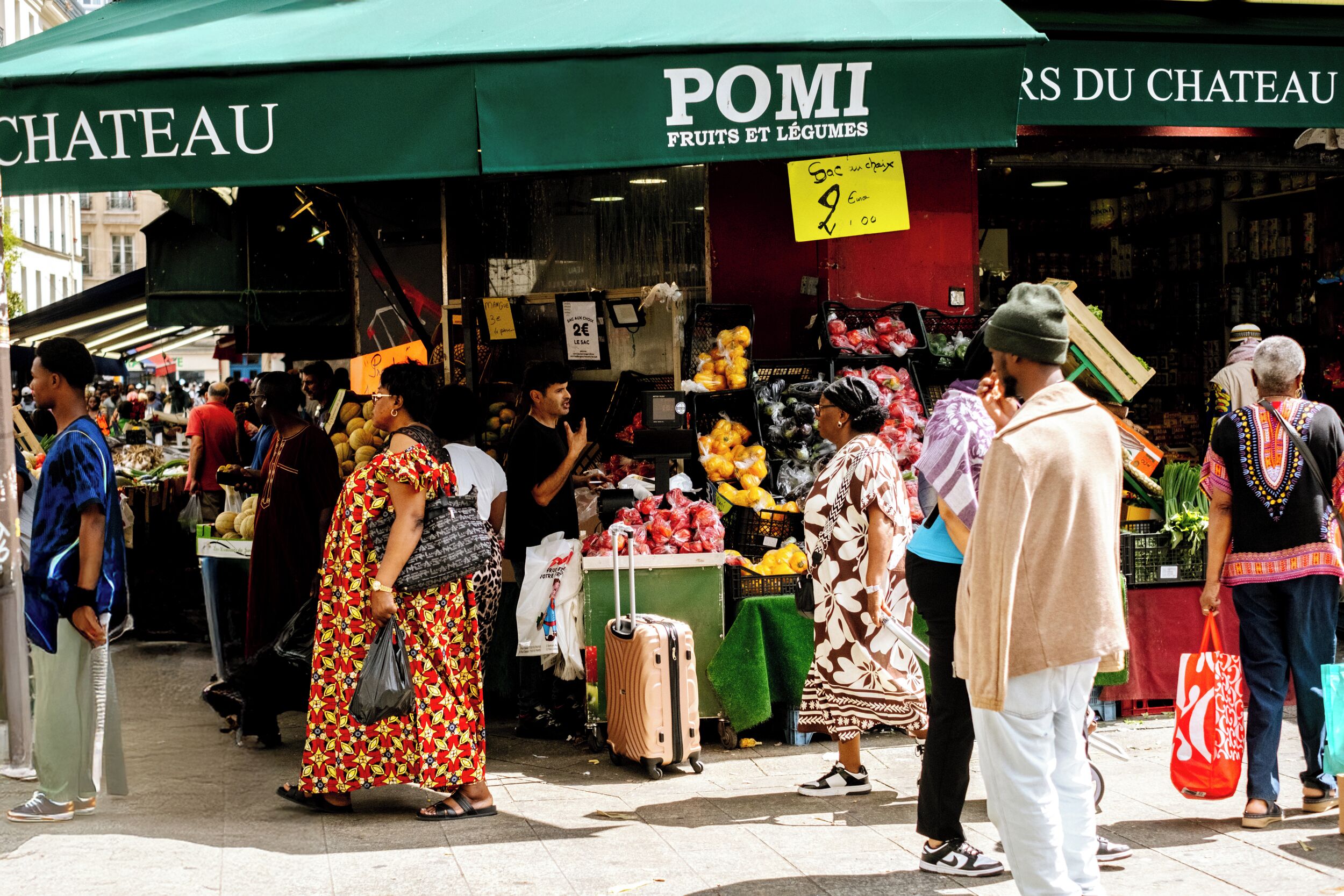 A bustling outdoor market with various stalls selling fruits and vegetables.