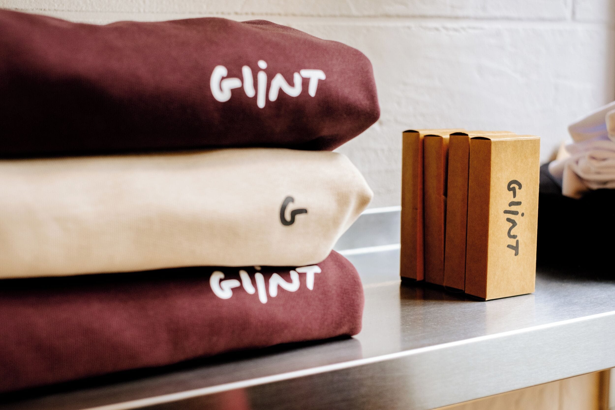 Una pila de toallas dobladas con el nombre de marca 'Glint' sobre una encimera.