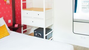 A bedroom with a bunk bed, a bedside table, a lamp, and a window with curtains.