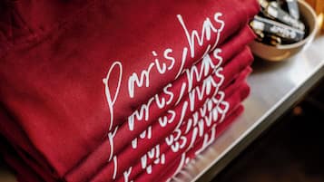Un tissu rouge orné d’un texte blanc en caractères cursifs, peut-être un sac-cadeau ou un sac fourre-tout, posé sur une surface métallique.