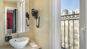 A bathroom with a large mirror, a white sink, and a hairdryer mounted on the wall.