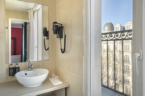 Ein Badezimmer mit einem großen Spiegel, einem weißen Waschbecken und einem an der Wand befestigten Föhn.