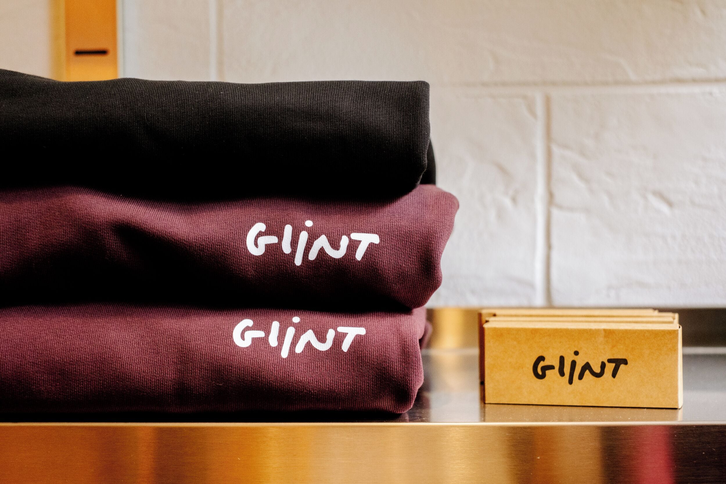 A stack of folded blankets labeled 'GLINT' on a wooden surface.