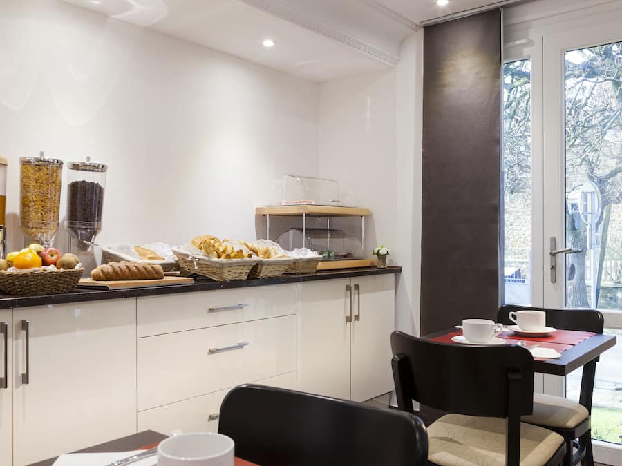 Une cuisine moderne avec des meubles blancs, un bar pour prendre le petit-déjeuner et un coin repas comprenant une table et des chaises.