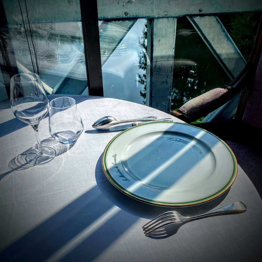 A table set with a plate, two wine glasses, a spoon, and a fork.