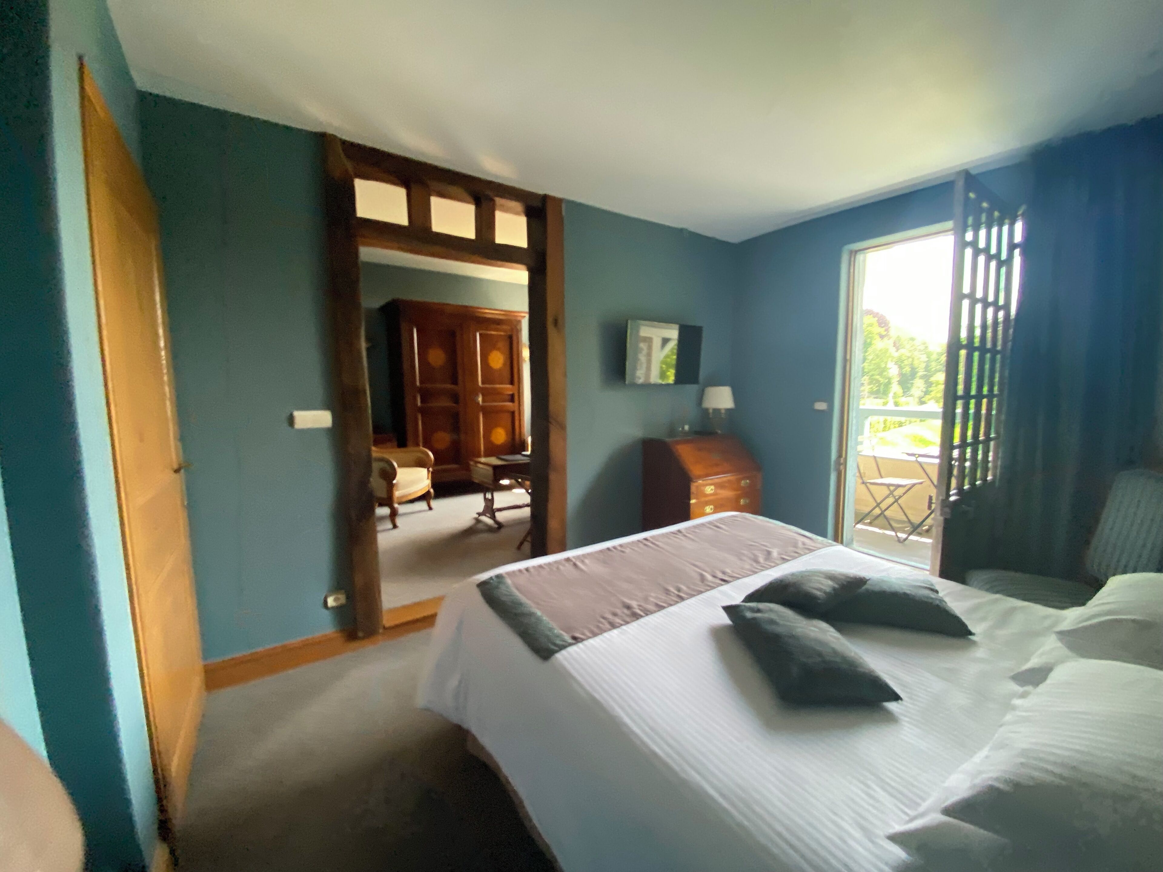 A bedroom with a bed, a dresser, a chair, and a view of the outdoors.
