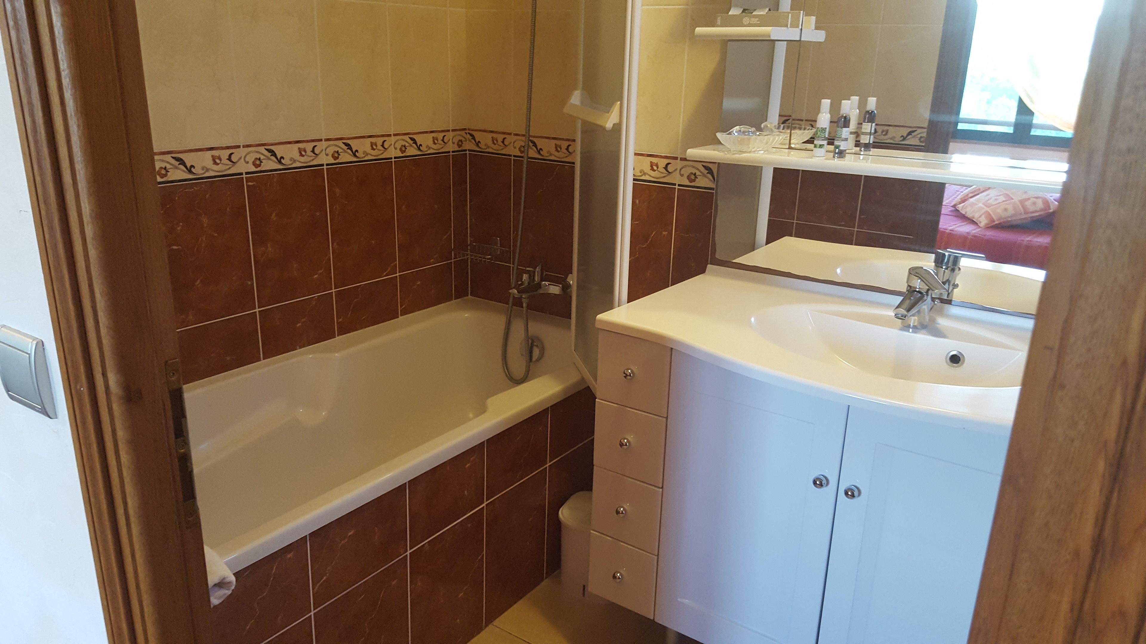 A bathroom with a bathtub, a sink, and a mirror.
